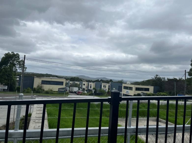 A fence with a black railing and grass and buildings

AI-generated content may be incorrect.